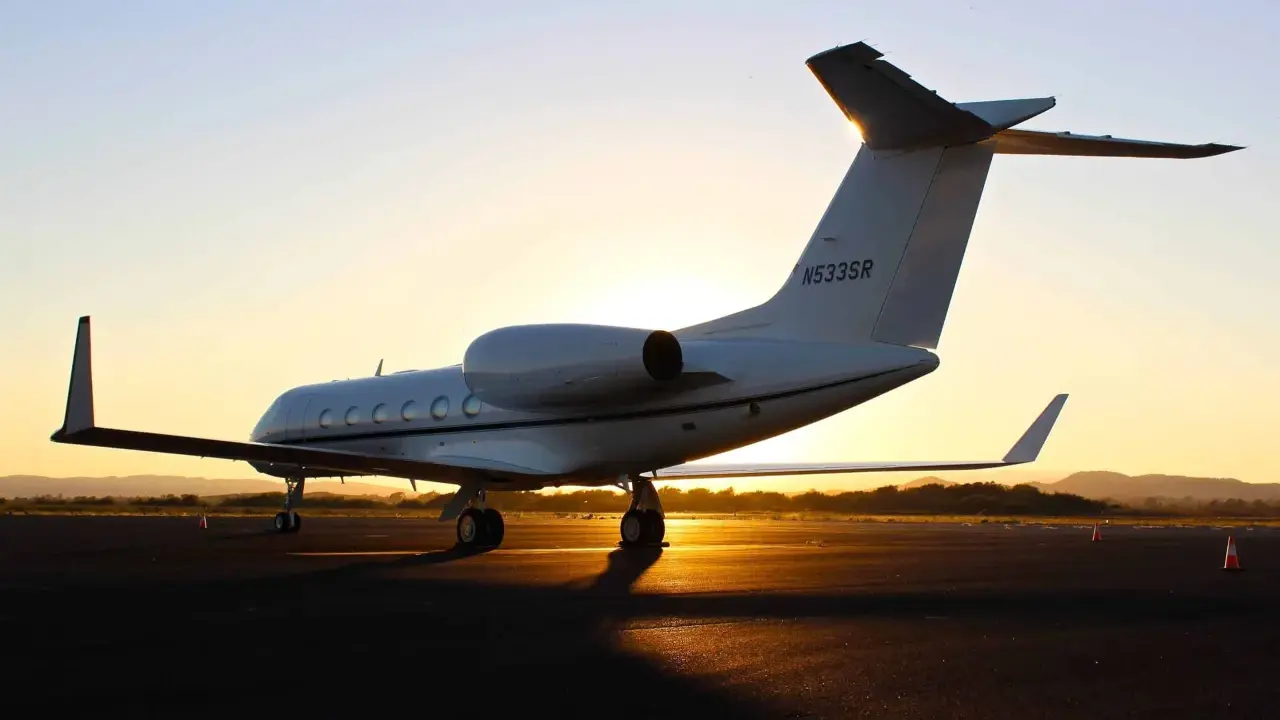Ein weißer Privatjet steht im Sonnenuntergang auf dem Rollfeld. Verschiedene privatjets modelle sind auf dem Markt, aber dieser hier strahlt Luxus aus.