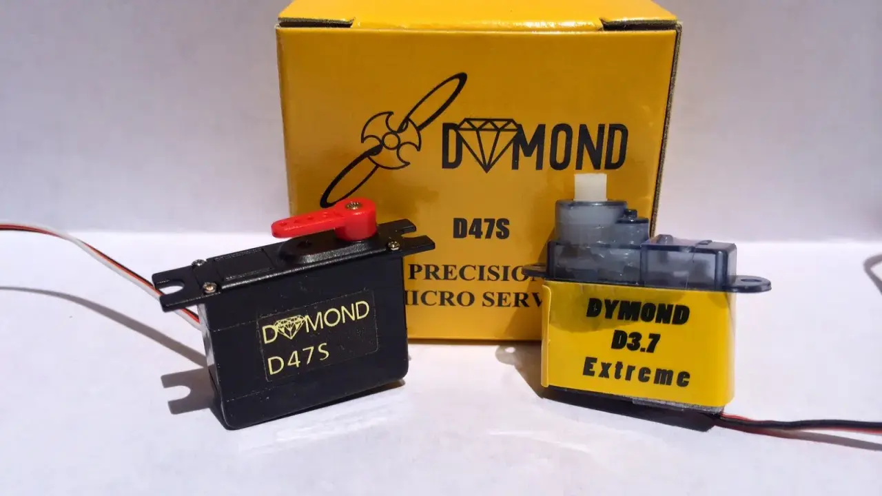 Zwei Servos, ein schwarzer Dymond D47S und ein gelber Dymond D3.7 Extreme, stehen vor einer gelben Box mit der Aufschrift "Dymond D47S".