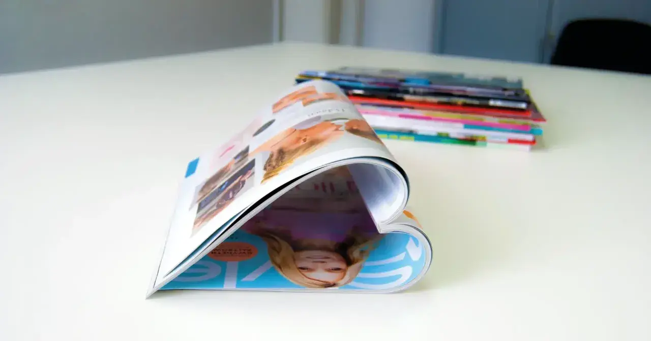 Ein aufgeschlagenes Magazin, das wie ein Herz geformt ist, liegt auf einem Tisch. Im Hintergrund stapeln sich weitere Ausgaben der aero zeitschrift.