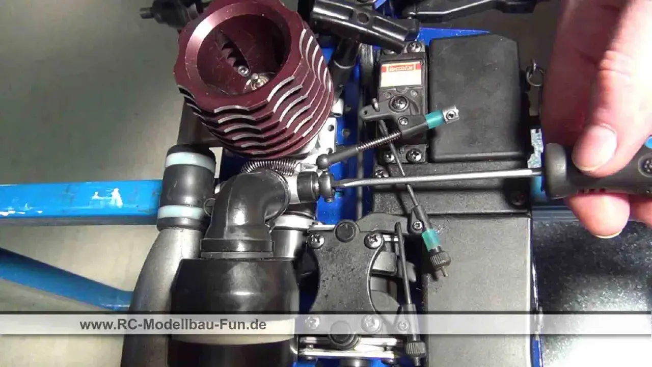 Nahaufnahme eines Nitromethan-Autos, bei dem eine Hand mit einem Schraubendreher an der Mechanik arbeitet.