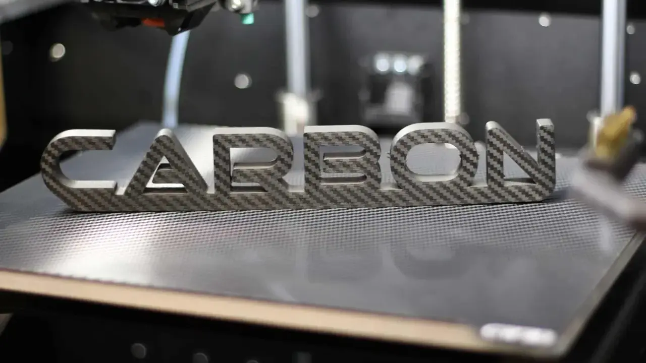 Ein 3D-Drucker fertigt das Wort "CARBON" aus einer Carbonplatte.