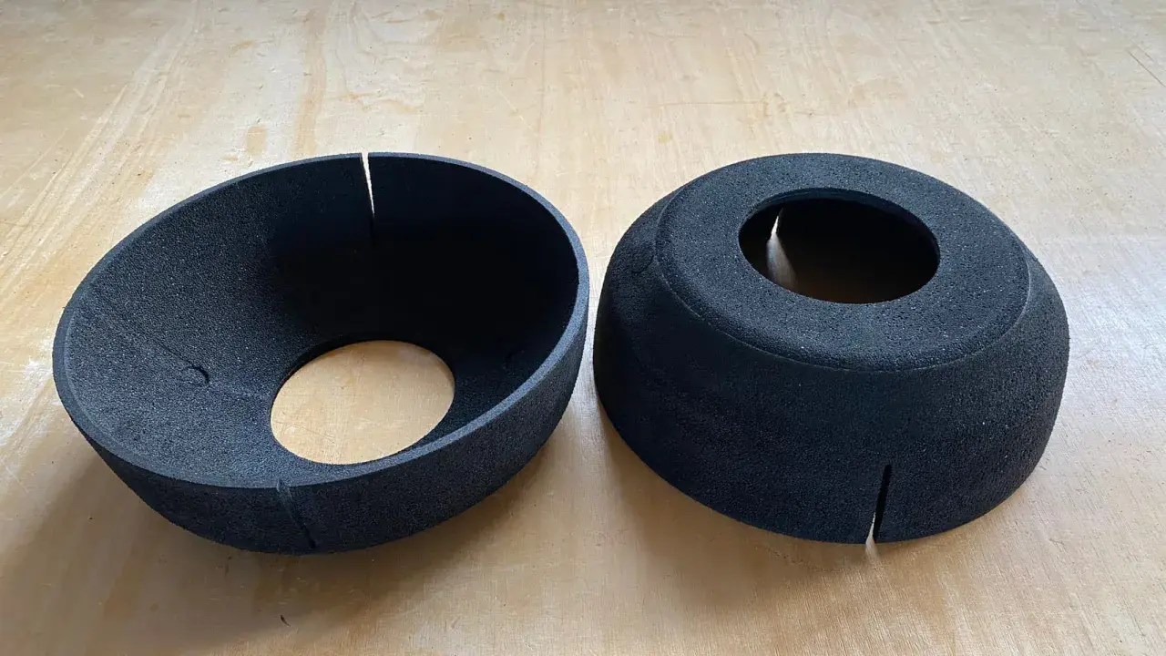 Zwei schwarze EPP-Platten, geformt wie Trichter und Zylinder, liegen auf einer Holzoberfläche.