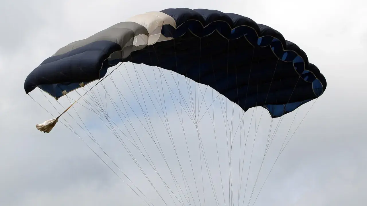 Ein großer, mehrfarbiger Fallschirm öffnet sich im Himmel, bereit für den Sprung aus dem Flugzeug.