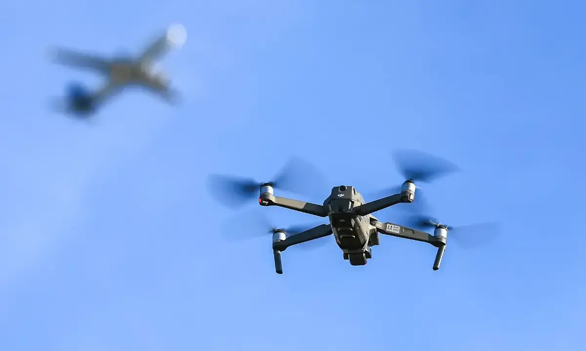 Drohne fliegt im Himmel, ein Flugzeug im Hintergrund. Wichtig: Drohne Haftpflicht für sichere Flüge.