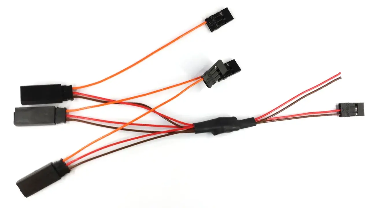 Ein dreiadriges Kabel mit mehreren schwarzen Steckern und bunten Leitungen, das für elektrische Verbindungen verwendet wird.