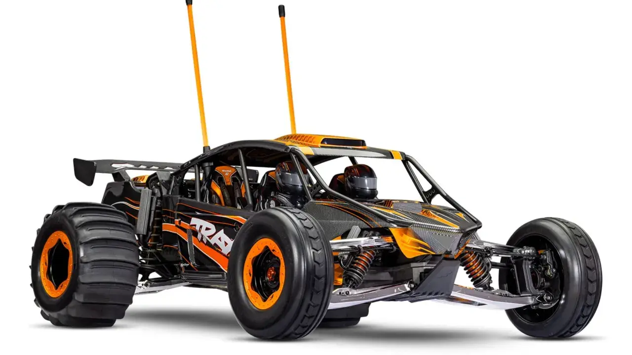 Schwarzes und orangefarbenes offroad elektroauto mit großen Reifen und zwei Antennen, bereit für jedes Abenteuer.