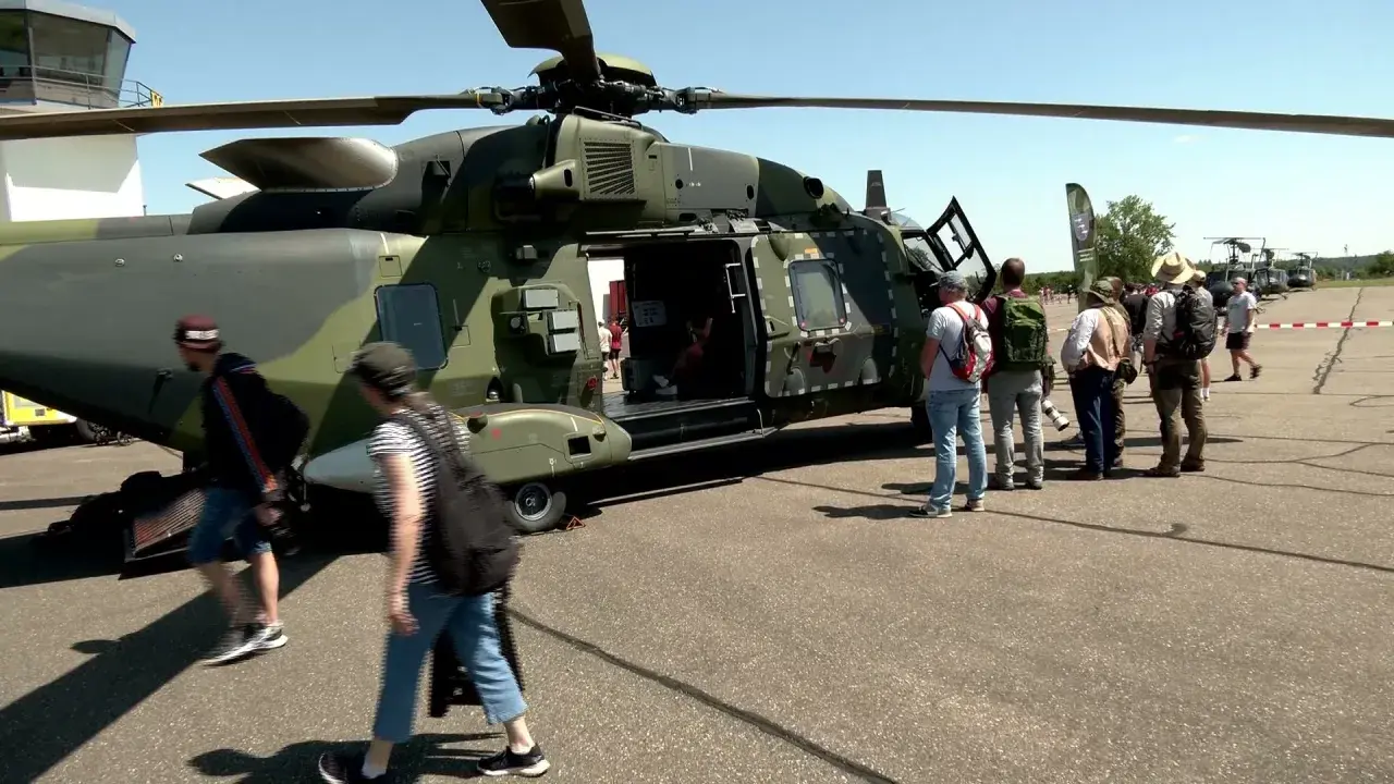 Besucher bestaunen deutsche Hubschrauber auf einem Flugplatz.