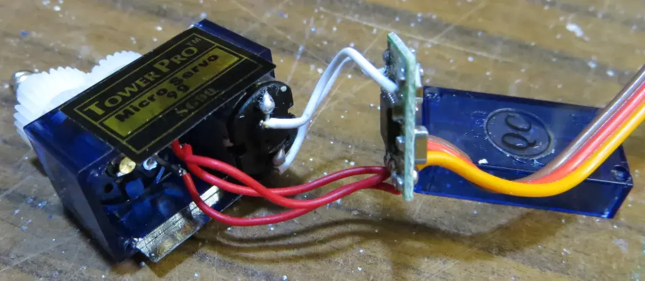 Ein Tower Pro Micro Servo mit Zahnrädern und einem 1m Verlängerungskabel, verbunden über eine kleine Platine.