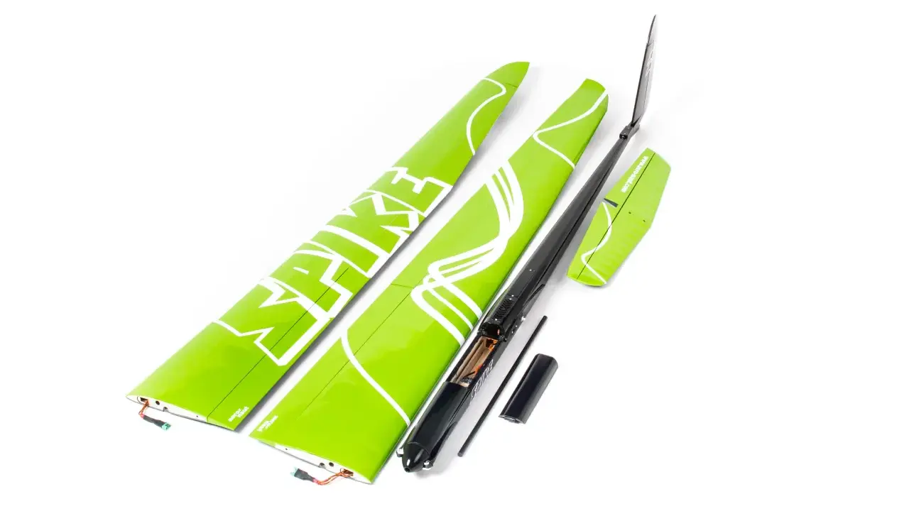 Grüne Flügelteile eines Modellflugzeugs mit weißer Schrift. Ein schwarzer Rumpf mit geöffnetem Batteriefach und 18 AWG Kabeln liegt daneben.