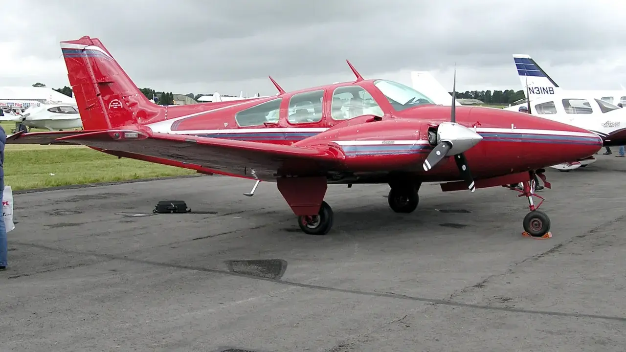 Roter Beechcraft Baron mit zwei Propellern auf dem Flugplatz.