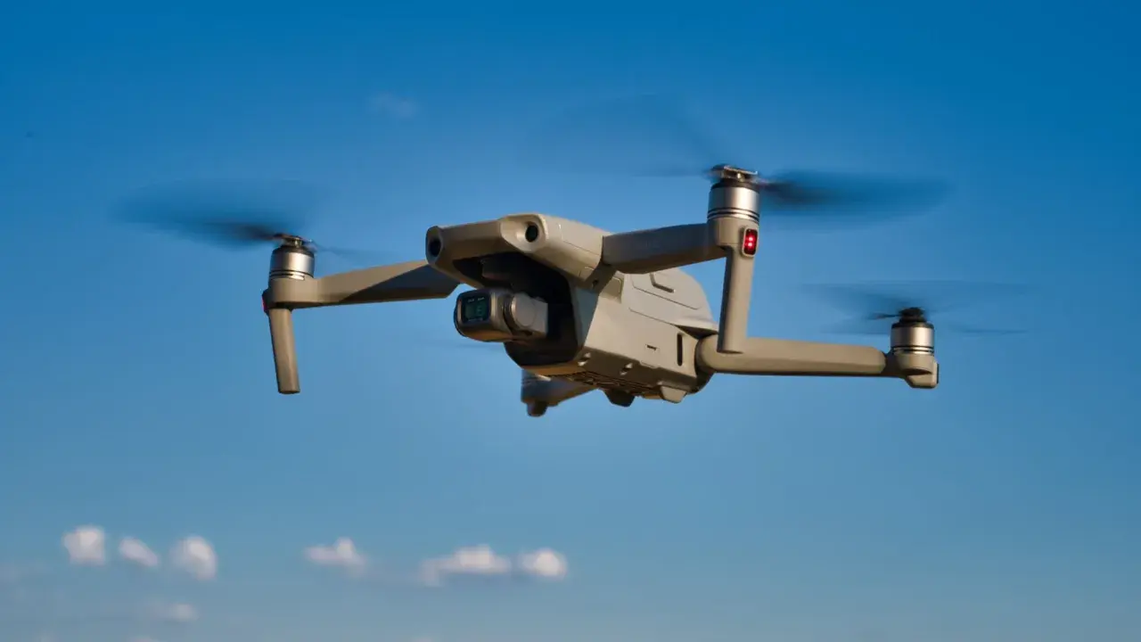 Grauer DJI Mavic Air 2 Drohne fliegt im blauen Himmel. Mit Drohnen Versicherung sind Sie sicher unterwegs.