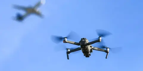 Drohne fliegt im Himmel, ein Flugzeug im Hintergrund. Wichtig: Drohne Haftpflicht für sichere Flüge.