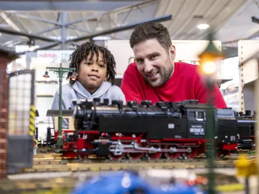 Vater und Sohn bestaunen detailreiche Modelleisenbahnen auf der Modellbaumesse Dortmund.