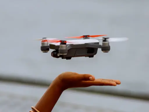 Kleine Drohne schwebt über einer Hand. Perfekt für den Einstieg, da sie die Drohne unter 250g Regeln erfüllt.