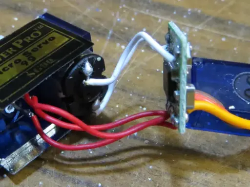 Ein Tower Pro Micro Servo mit Zahnrädern und einem 1m Verlängerungskabel, verbunden über eine kleine Platine.