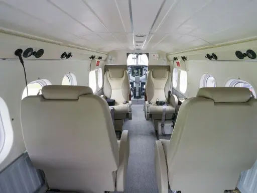 Innenraum einer DHC-6 Twin Otter mit bequemen Ledersitzen und Blick auf das Cockpit.