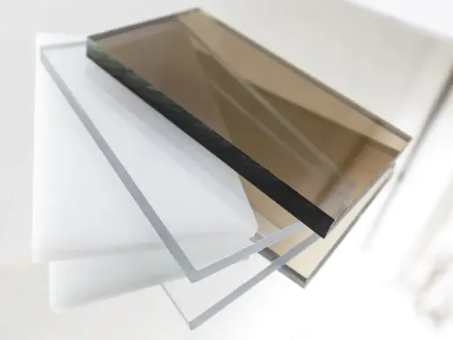 Stapel von transparenten und braunen Polycarbonatplatten. Die Kanten zeigen die Dicke und die Möglichkeit, Polycarbonat zu lackieren.