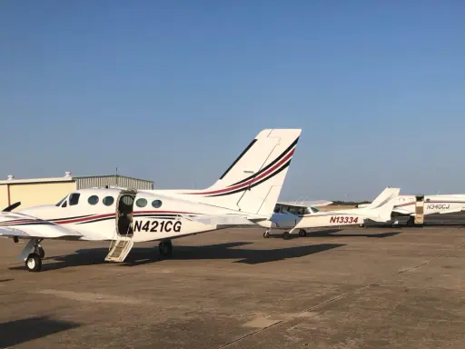 Mehrere weiße Cessna zweimotorig Flugzeuge stehen auf dem Flugplatz. Eines hat die Tür geöffnet.