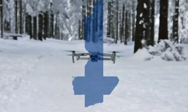 Eine Drohne fliegt über eine verschneite finnische Landschaft. Die Silhouette Finnlands ist über das Bild gelegt.