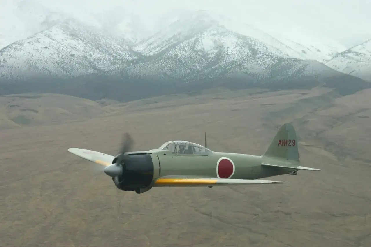 Ein A6M5 Zero-Jäger fliegt über eine bergige Landschaft.