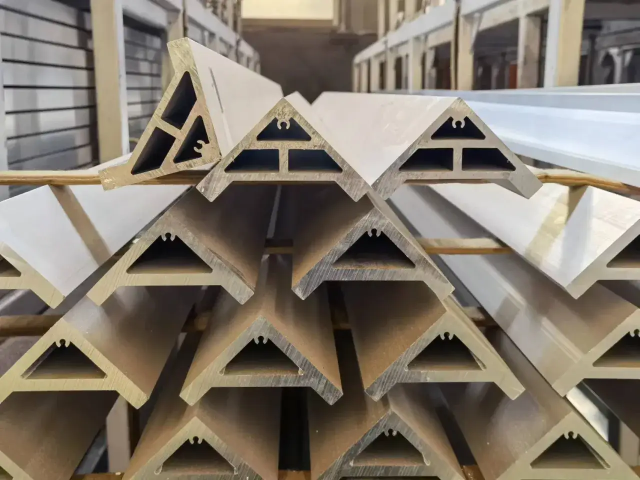 Stapel von Aluminiumprofilen mit dreieckigem Querschnitt, bereit für den Einsatz in Bauprojekten.
