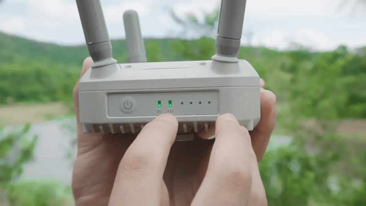Hände halten eine DJI Antenne mit zwei grünen Lichtern, die RC und UAV anzeigen.