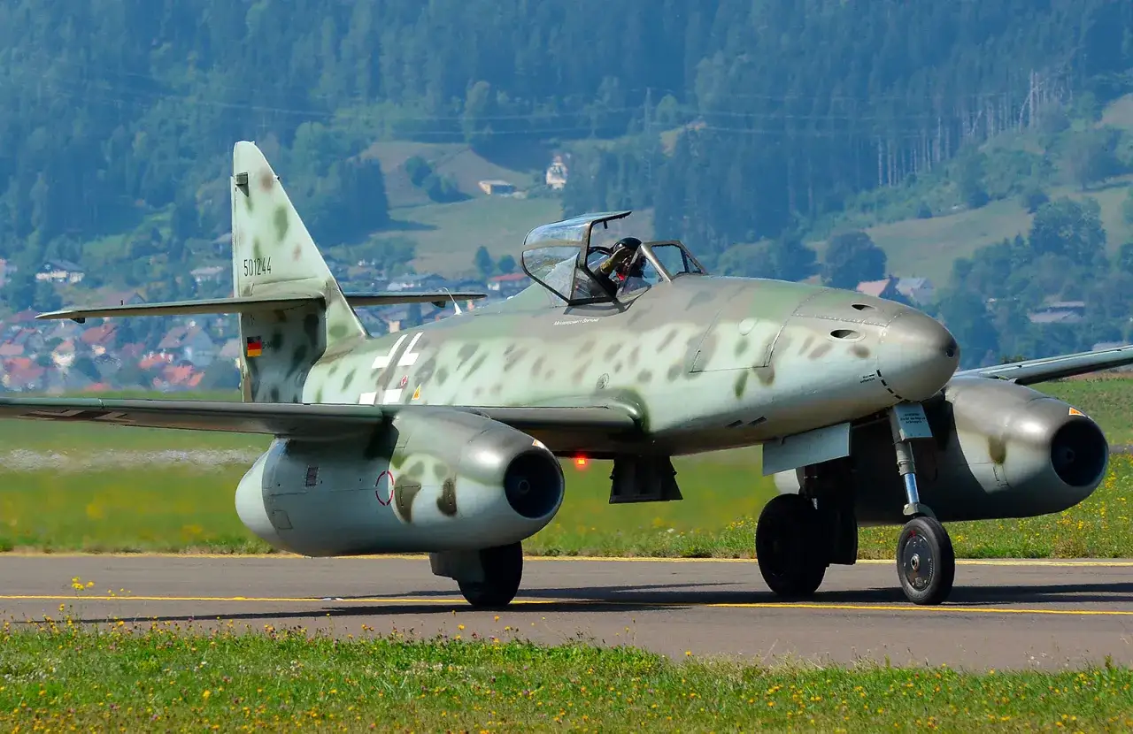 Ein deutscher Jet, eine Messerschmitt Me 262, rollt auf dem Rollfeld. Die Tarnlackierung ist gut erkennbar.