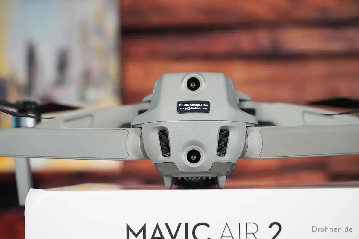 Graue Drohne Mavic Air 2 mit Propellern, die auf einer weißen Box steht. Ein Aufkleber mit der drohne id und shop@drohnen.de ist sichtbar.