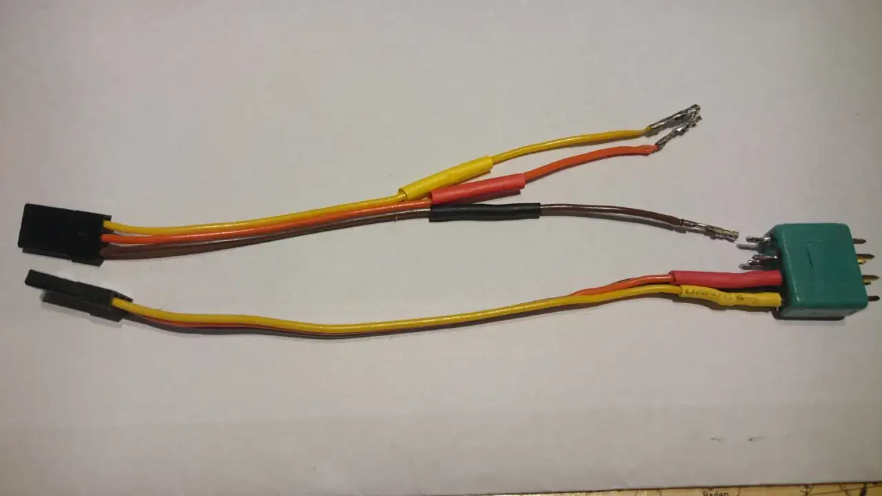Zwei Kabelstränge mit verschiedenen Steckern und Drähten, einer mit einem schwarzen Stecker, der andere mit einem grünen Stecker.