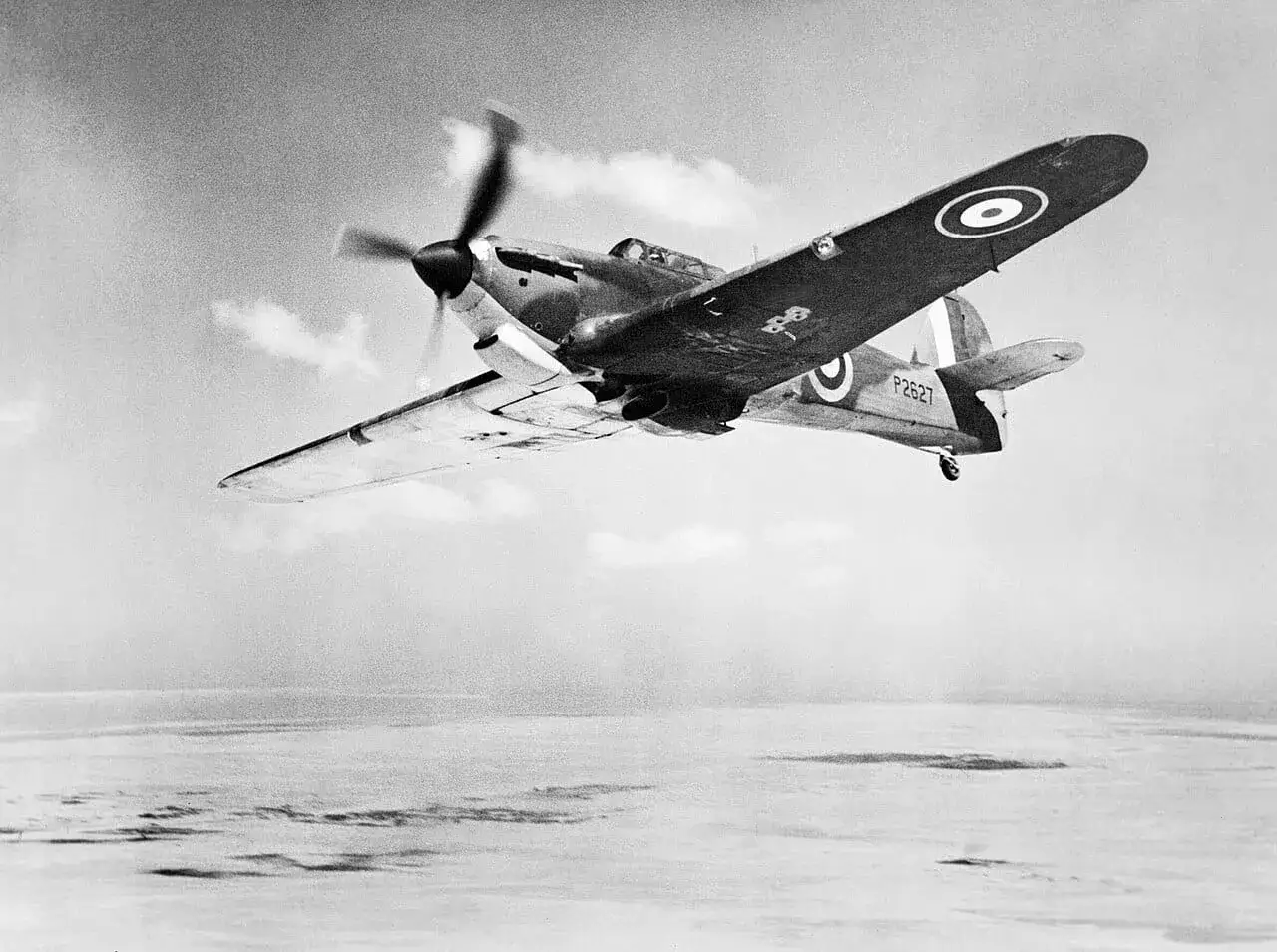 Ein Hurricane-Flugzeug fliegt über eine neblige Landschaft.