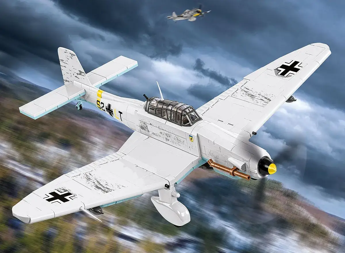 Ein weißes Ju 87 Stuka-Modell fliegt durch dramatische Wolken. Ein weiteres Flugzeug ist im Hintergrund zu sehen.
