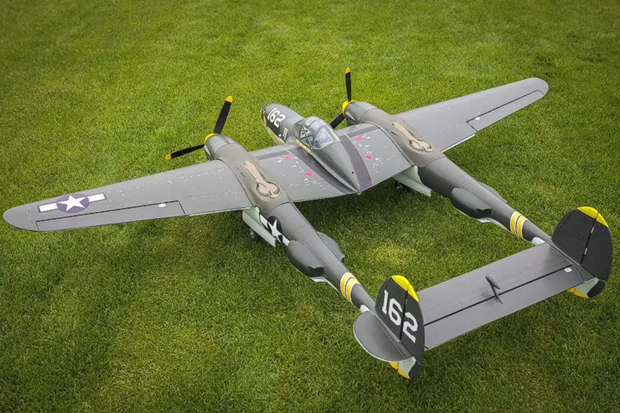P-38 Lightning RC-Modellflugzeug auf grünem Rasen. Das Modell hat eine graue Lackierung mit gelben Akzenten und der Nummer 162.