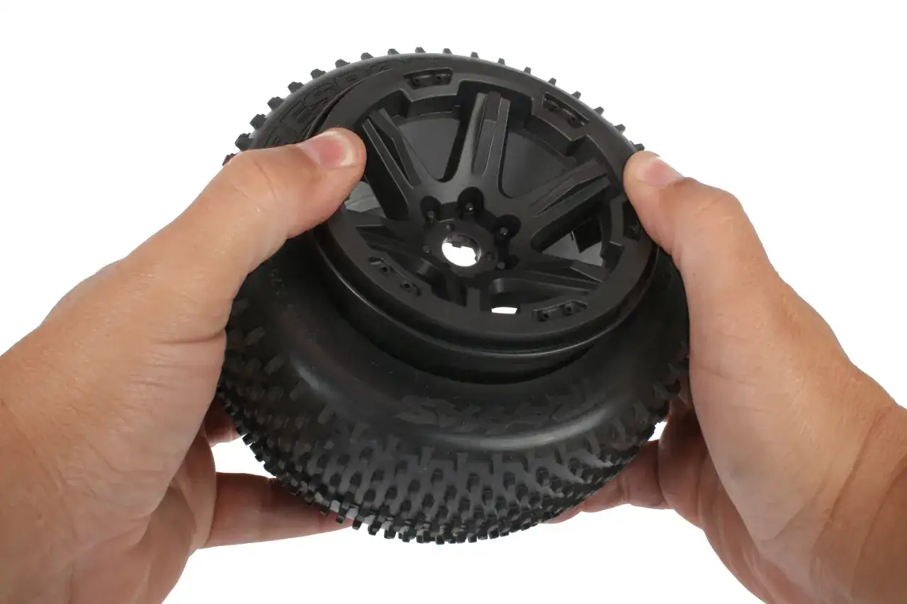 Hände halten ein RC-Auto-Rad, um die Reifen zu kleben.