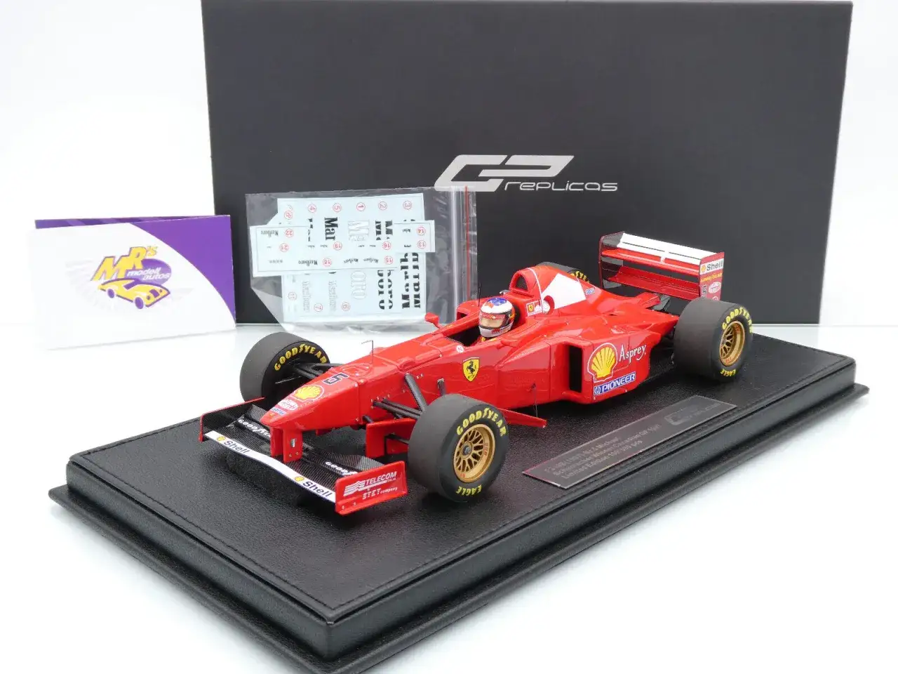 Ein rotes Ferrari F1-Modellauto, das teuerstes RC-Auto der Welt, mit detaillierten Sponsorenaufklebern und auf einem schwarzen Sockel präsentiert.