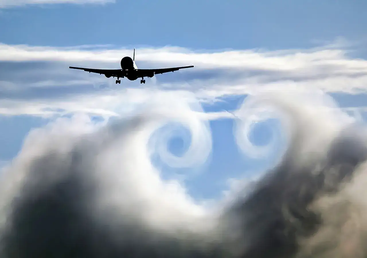 Ein Flugzeug fliegt durch den Himmel, hinterl&auml;sst Wirbel im Jetstream.