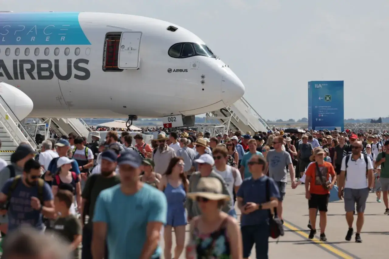 Menschenmassen drängen sich vor einem Airbus-Flugzeug. Ein Schild weist auf die ILA Berlin hin, eine Flugshow, die Besucher begeistert.