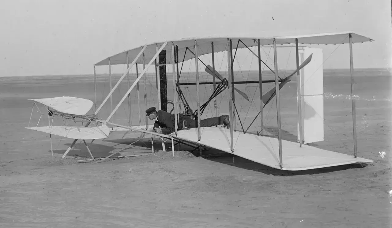 Ein Mann liegt auf dem Kitty Hawk Flugzeug, bereit zum Start.