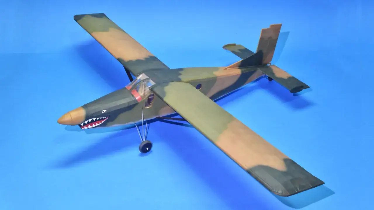 Modellflugzeug Pilatus PC-6 mit Haifischmaul-Bemalung auf blauem Hintergrund.
